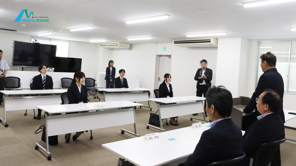 モバイルクリエイトの内定式で、内定者が代表の話を聞く様子。