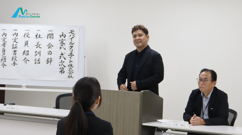 モバイルクリエイト内定式で、代表が内定者に向けて挨拶を行う場面。