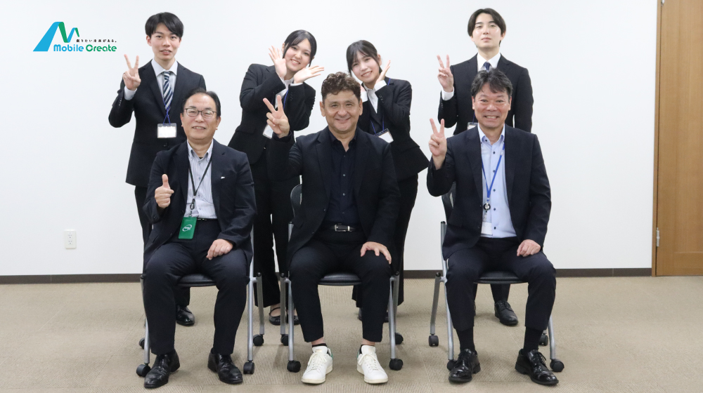 モバイルクリエイト内定式後の記念撮影。役員と内定者が笑顔でポーズ。