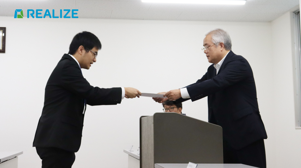 REALIZEの内定式で、代表から内定証書を受け取る内定者。