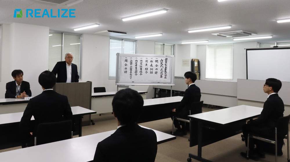 REALIZEの内定式で、代表が内定者に向けて挨拶を行う場面。