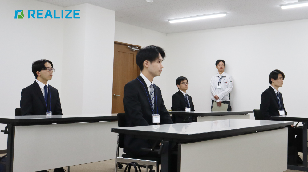 REALIZEの内定式で、内定者が代表の話を聞く様子。