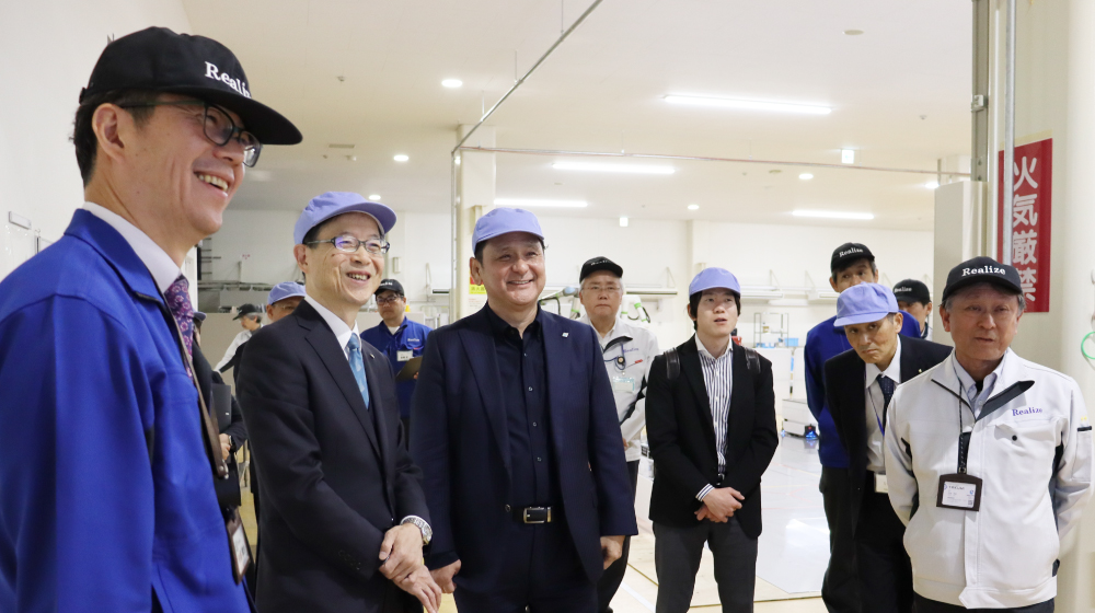 REALIZEの工場内で関係者が説明を受けながら意見交換を行っている様子