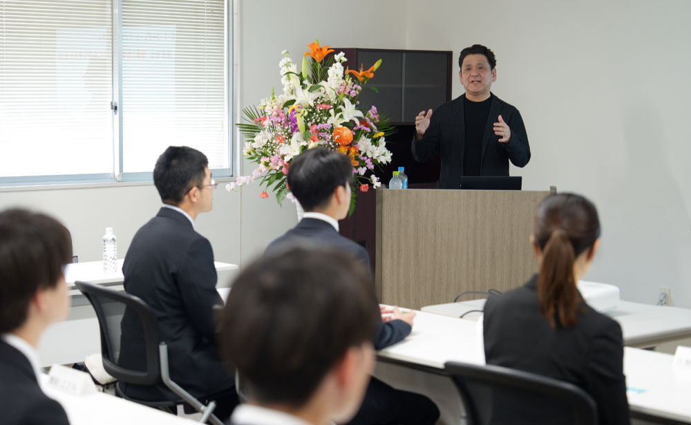 FIGグループ合同入社式で、代表取締役社長が新入社員に向けて挨拶を行う様子。