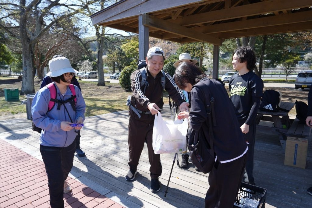 高崎山ハイキング出発前に幹事から飲み物や軽食が配布される様子