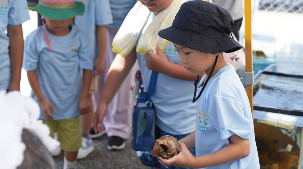 タッチプールで海の生きものを観察する子ども